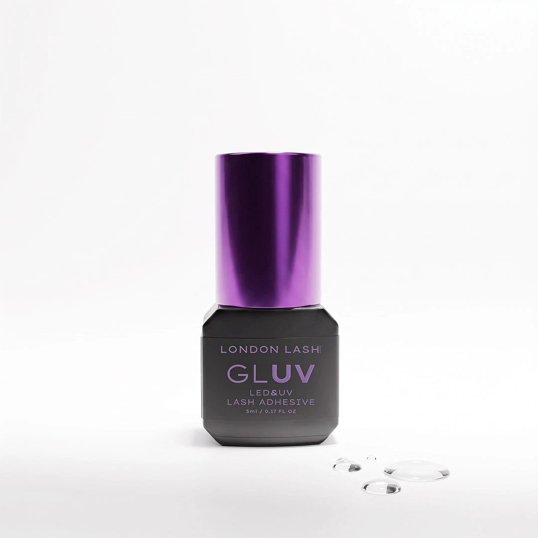 London Lash GLUV LED &amp; UV Lash Adhesive 5ml bottle with a metallic purple cap alongside clear adhesive droplets on a white background.